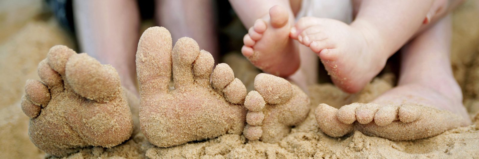 family feet on sandy beach