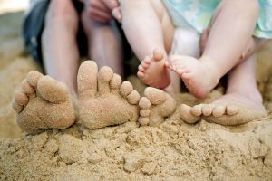 family feet on sandy beach